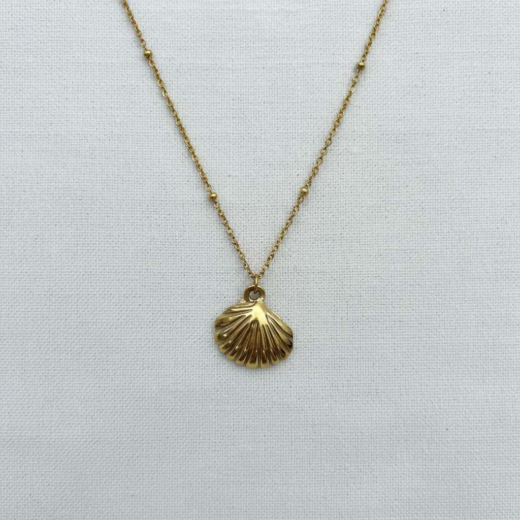 Gold shell pendant with symmetrical bead details on white linen